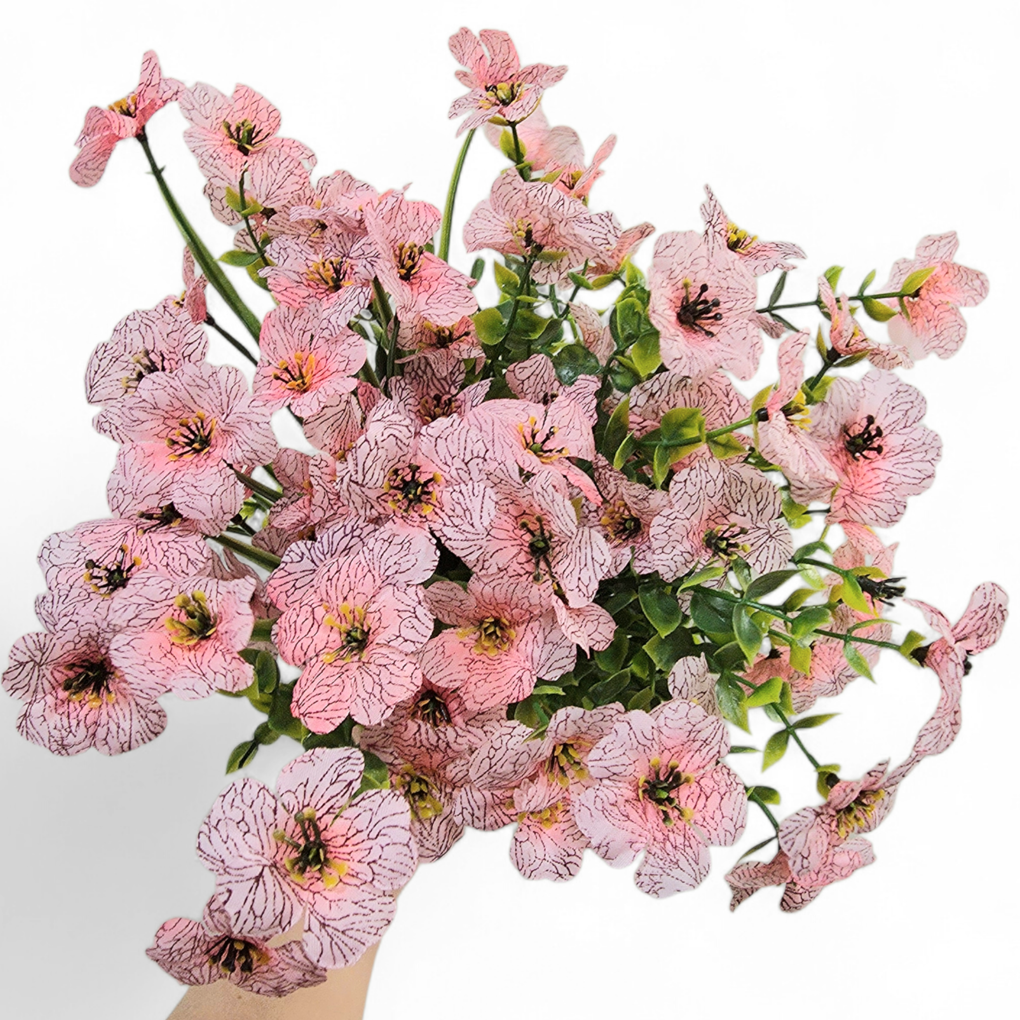 Bouquet of light pink flowers held by a hand on a white background