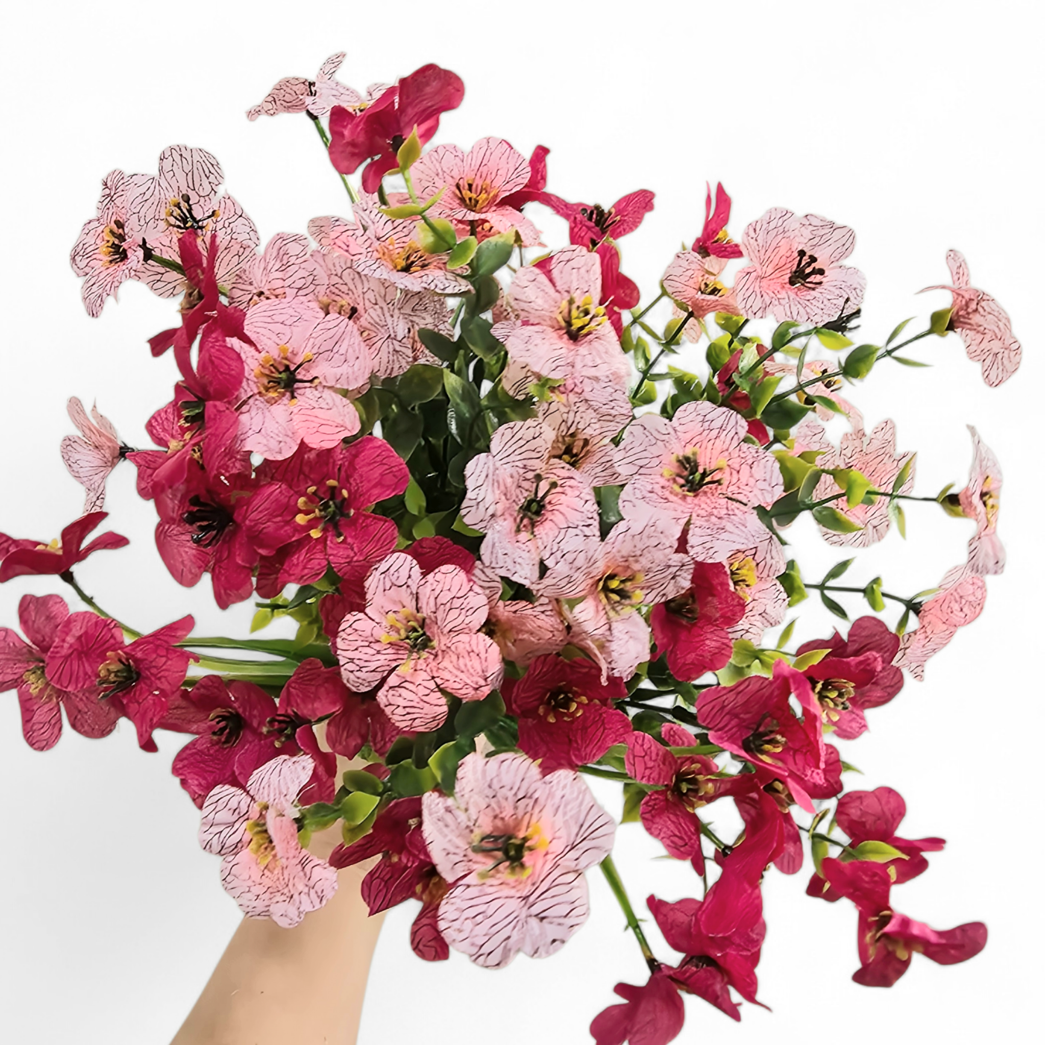 Bouquet of pink and cerise flowers held by a hand on a white background