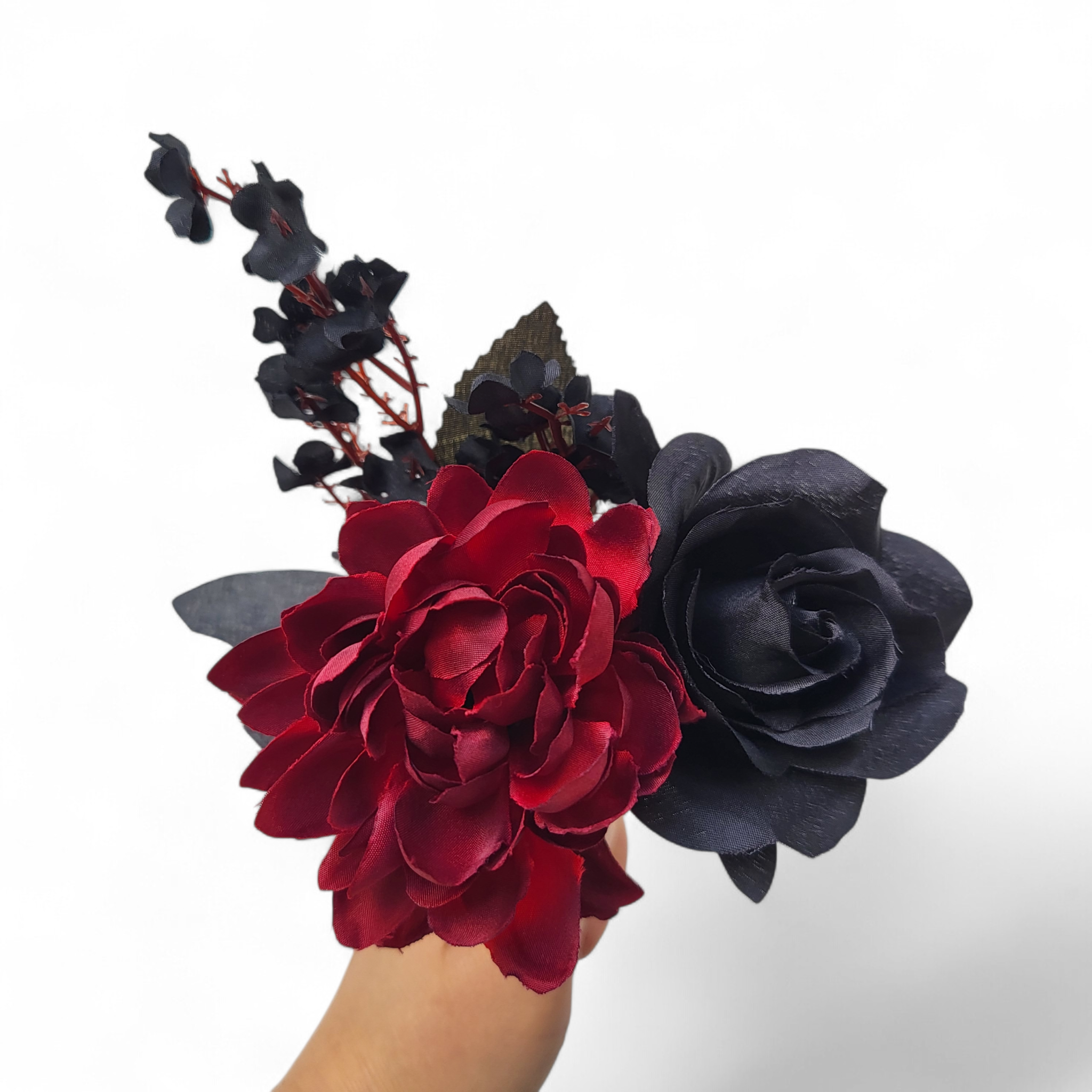 Red and black flowers held by a hand on a white background