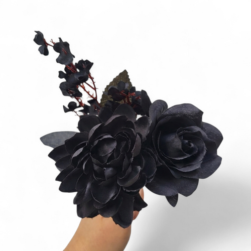 Bouquet of black flowers held by a hand on a white background