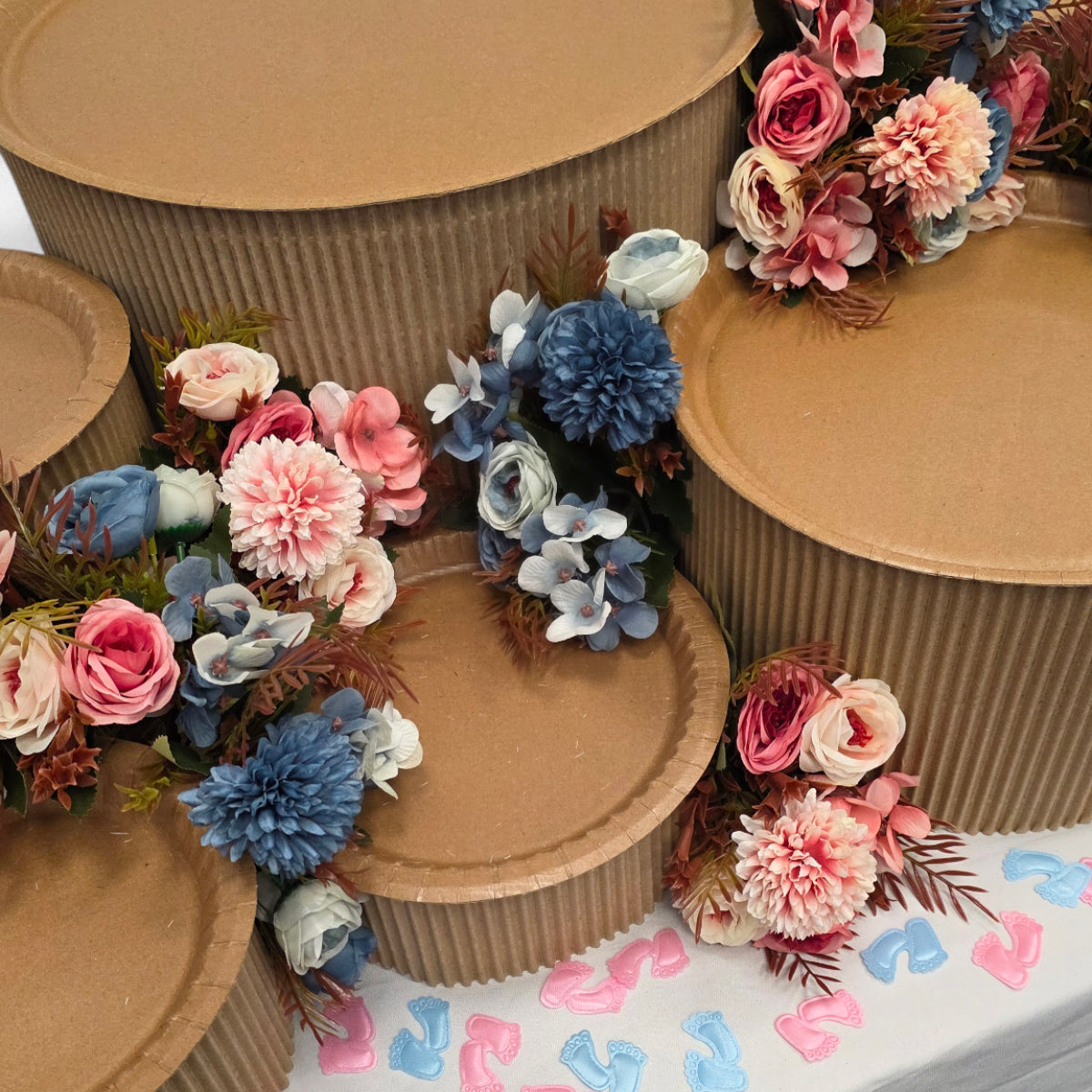 DIY grazing table kit baby shower gender reveal with disposable natural platters plinths, pink and blue flowers, baby footprint confetti and a "girl or boy?" sign detail view - grazekits