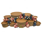 DIY grazing table kit baby shower gender reveal with disposable natural platters plinths, pink and blue flowers, baby footprint confetti and a "girl or boy?" sign left view - grazekits