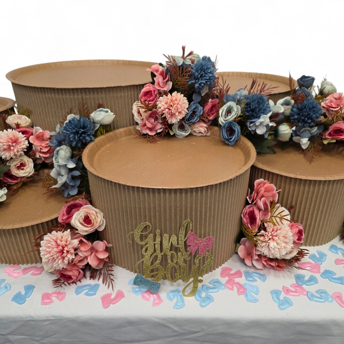 DIY grazing table kit baby shower gender reveal with disposable natural platters plinths, pink and blue flowers, baby footprint confetti and a "girl or boy?" sign front view - grazekits