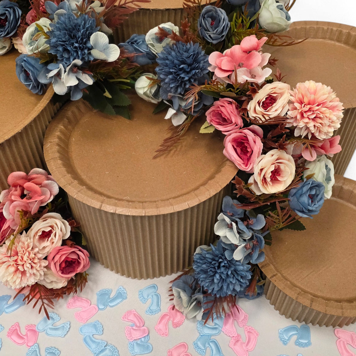 DIY grazing table kit baby shower gender reveal with disposable natural platters plinths, pink and blue flowers, baby footprint confetti and a "girl or boy?" sign detail view - grazekits